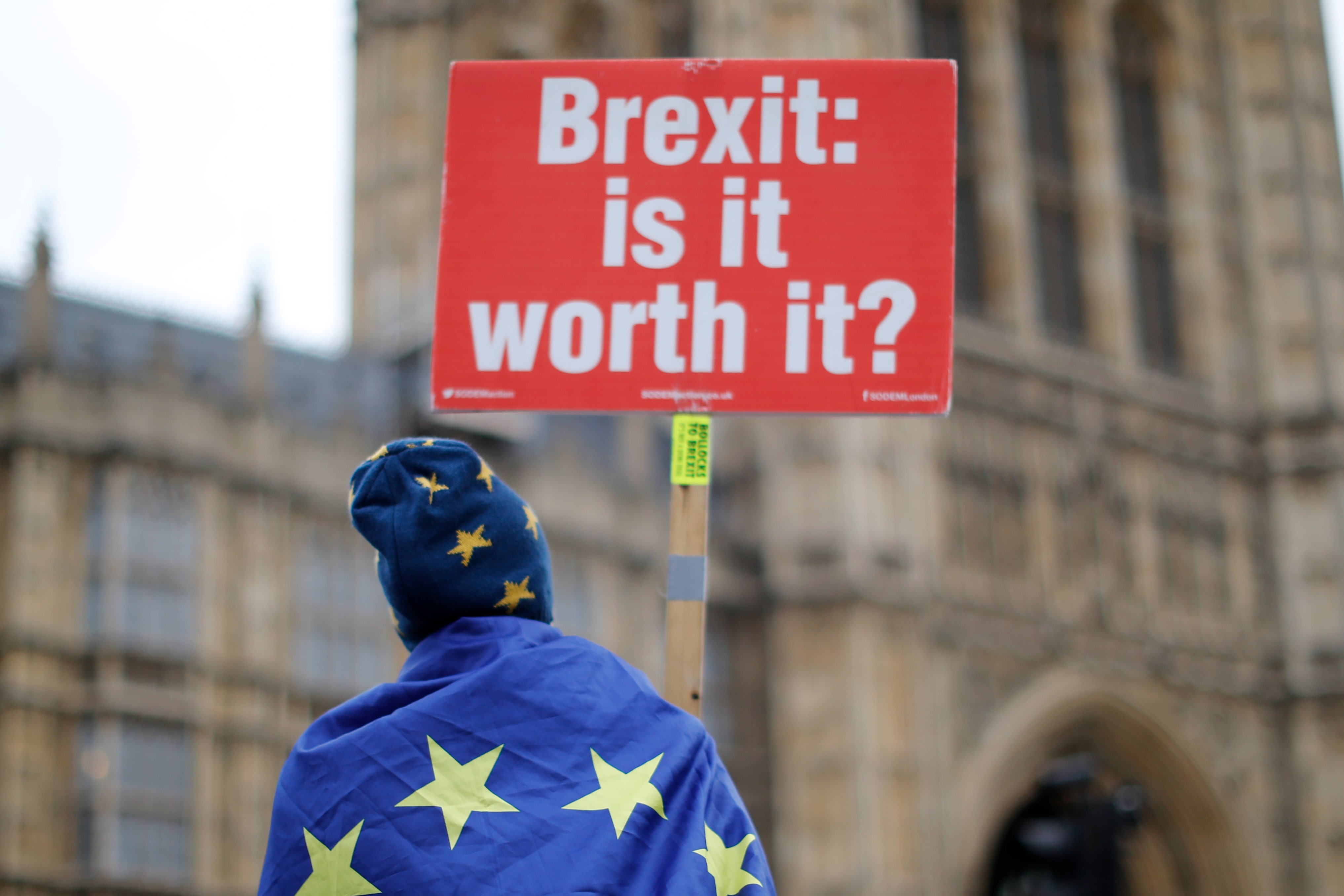 Anti-Brexit supporters hold placards and flags as they demonstrate outside the Houses of Parliament on 14  January (AFP)