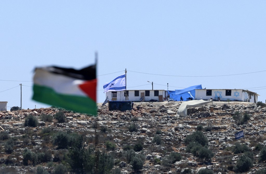 A Palestinian flag flutters on a hilltop in the town of Beita near Nablus city in the occupied West Bank near a settler outpost of Eviatar in the background. (AFP)
