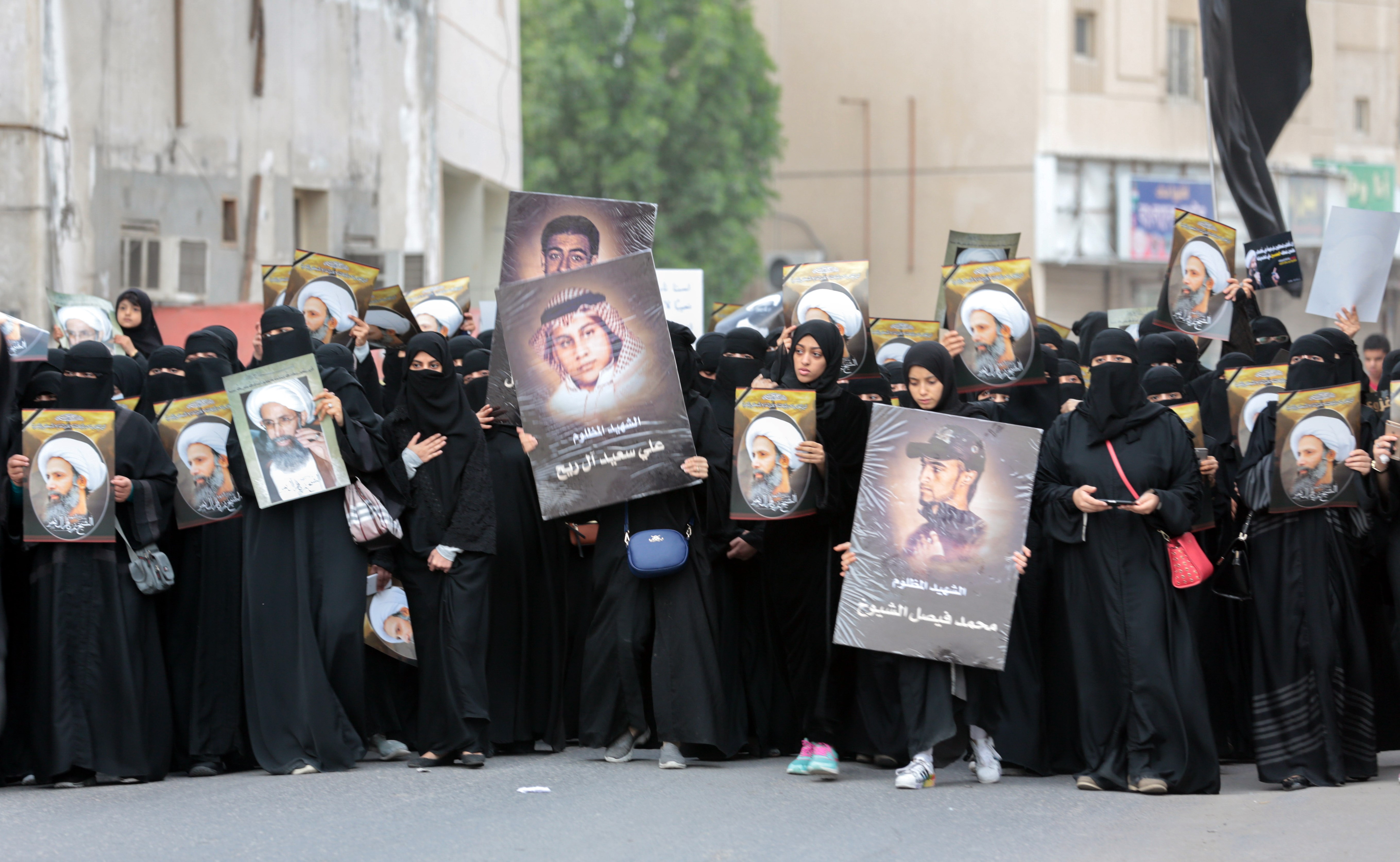 Saudi Shiite women hold placards bearing a portrait of prominent Shiite Muslim cleric Nimr al-Nimr during a protest on 8 January, 2016 in Qatif (AFP)