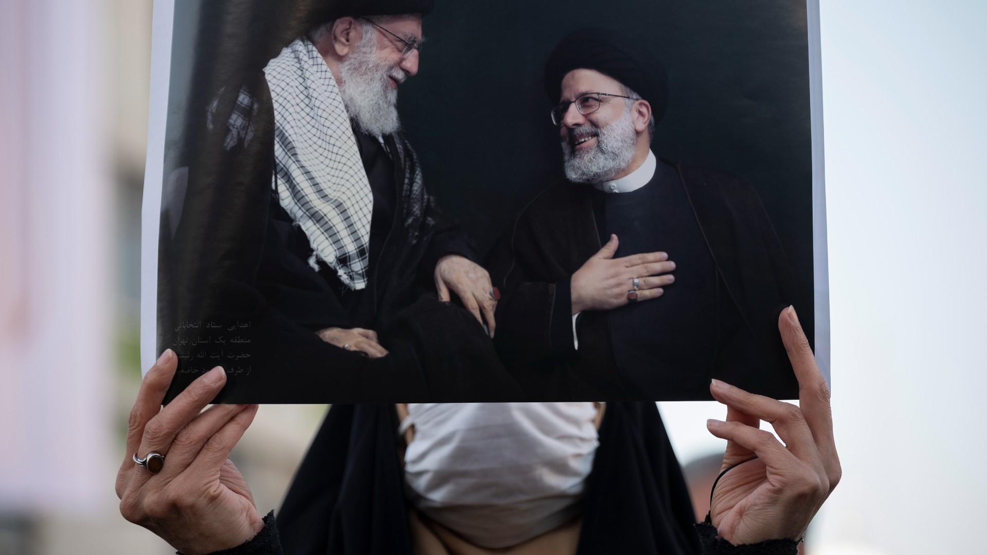 A supporter of Ebrahim Raisi holds an image with portraits of him and Supreme Leader Ayatollah Ali Khamenei, left, during the 2021 presidential election (Reuters)