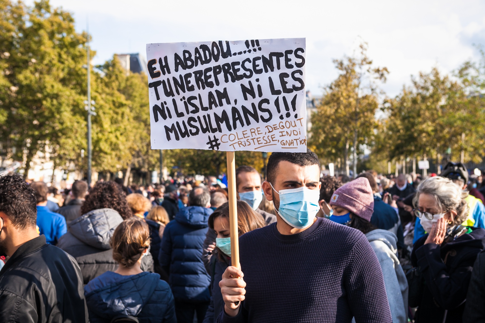 A demonstrators holds a sign addressed to the killer of Samuel Paty reading “Hey Abadou, you don’t represent Islam nor Muslims” during a rally in Paris on  on 18 October 2020 (Reuters)