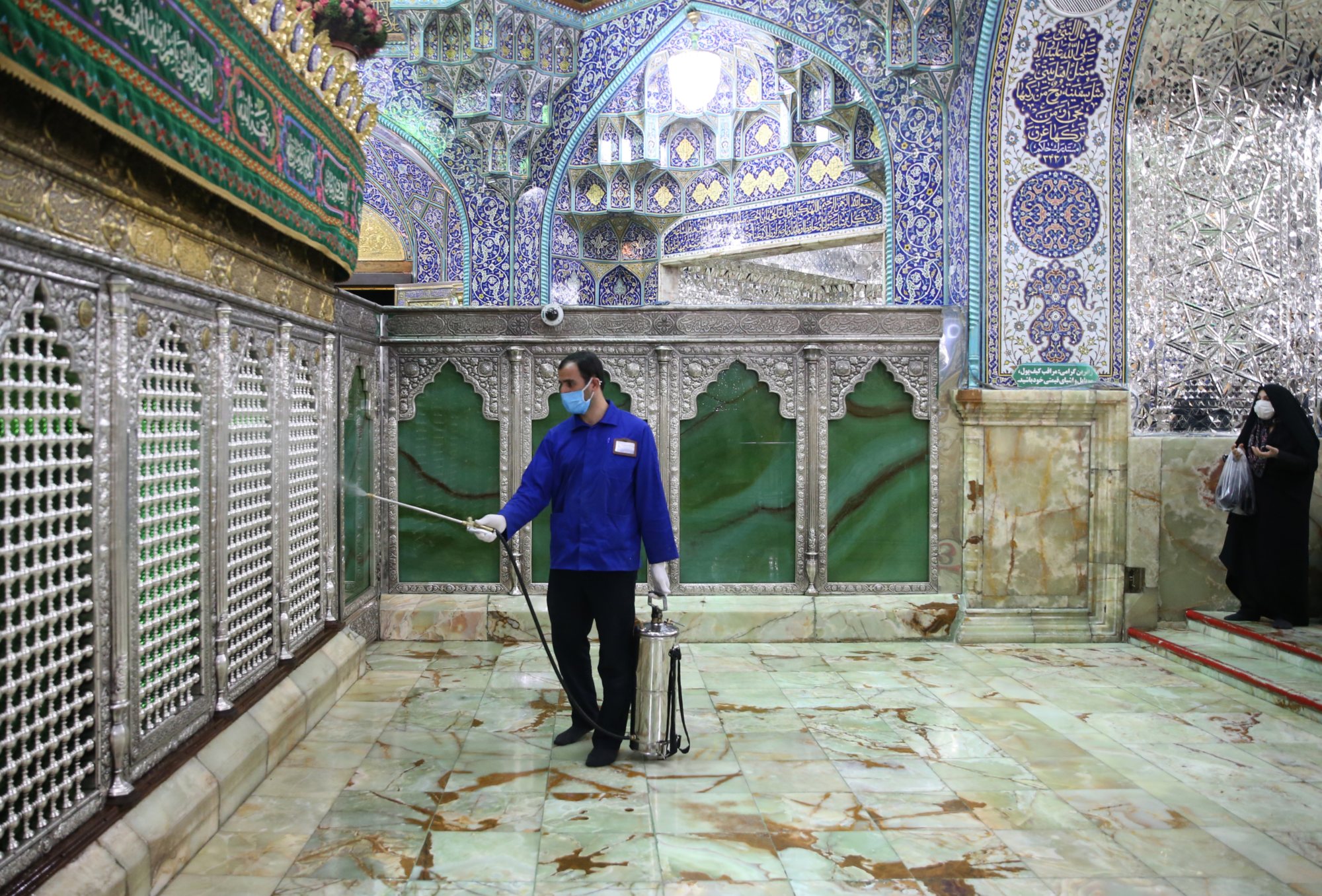 An Iranian sanitary worker disinfects Qom's Masoumeh shrine on 25 February 2020 to prevent the spread of the coronavirus (AFP)