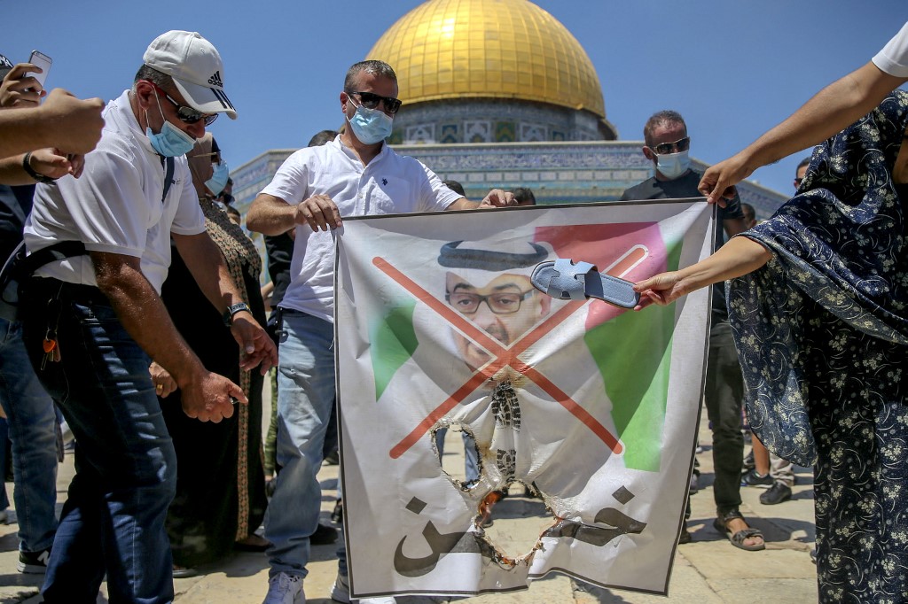 Palestinian protesters prepare to tear apart a portrait of Abu Dhabi Crown Prince Mohammed bin Zayed at al-Aqsa compound on 14 August (AFP)