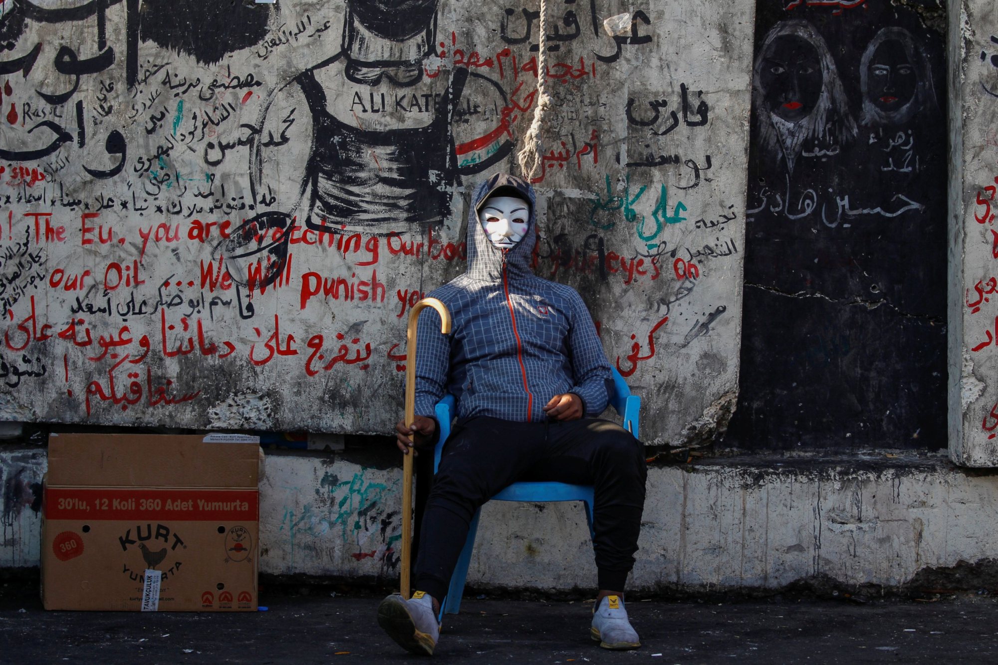An Iraqi demonstrator sits wearing a mask during the ongoing anti-government protests in Baghdad, Iraq on 22 November 2019 (Reuters)