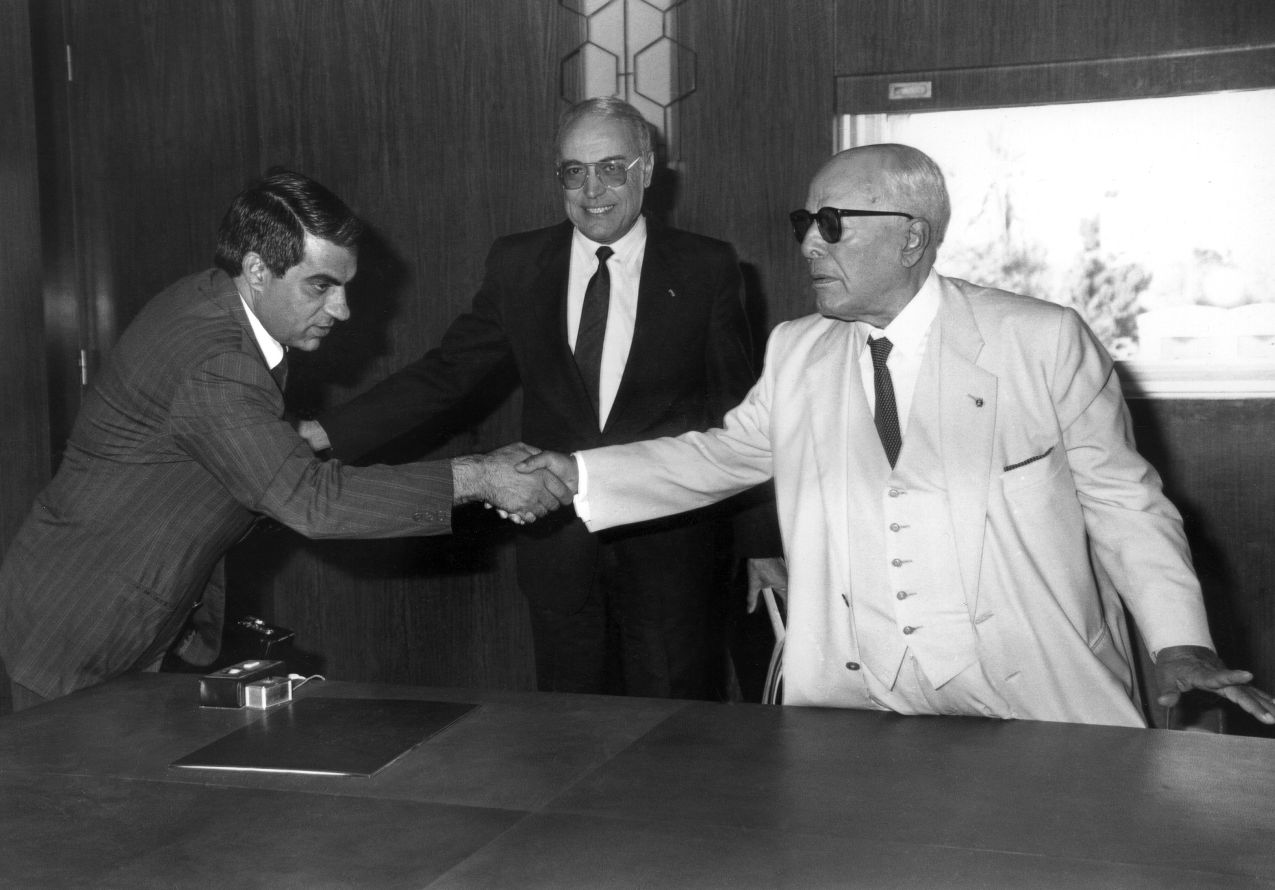 Tunisian President for Life Habib Bourguiba, right, shakes hands in 1986 in Tunis with his prime minister, Zine el Abidine Ben Ali, left (AFP)