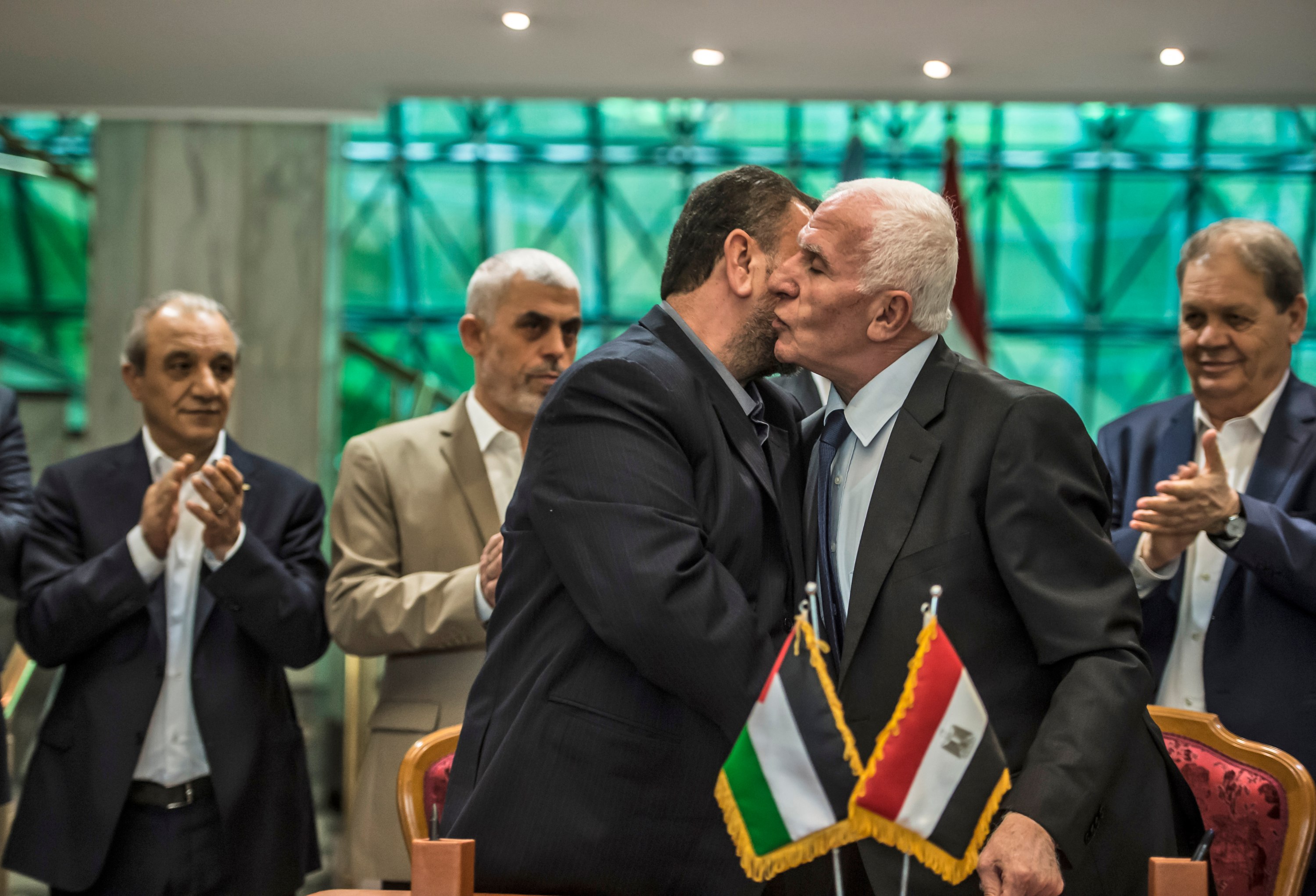 Fatah's Azzam al-Ahmad, right, and Saleh al-Aruri of Hamas kiss after signing a reconciliation deal in Cairo on 12 October 2017. The deal however failed to durably resolve the enmity between the two Palestinian parties (AFP)