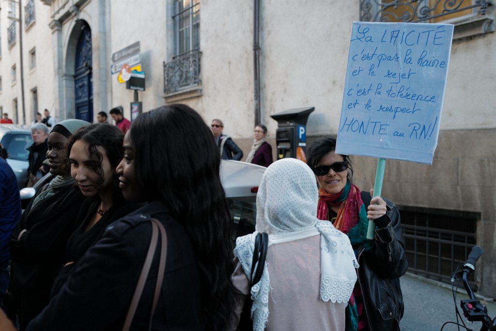 A woman holds a sign reading: ‘Secularism is not hatred and rejection, but tolerance and respect’, as people protest in support of a veiled woman who was targeted in eastern France on 16 October (AFP)