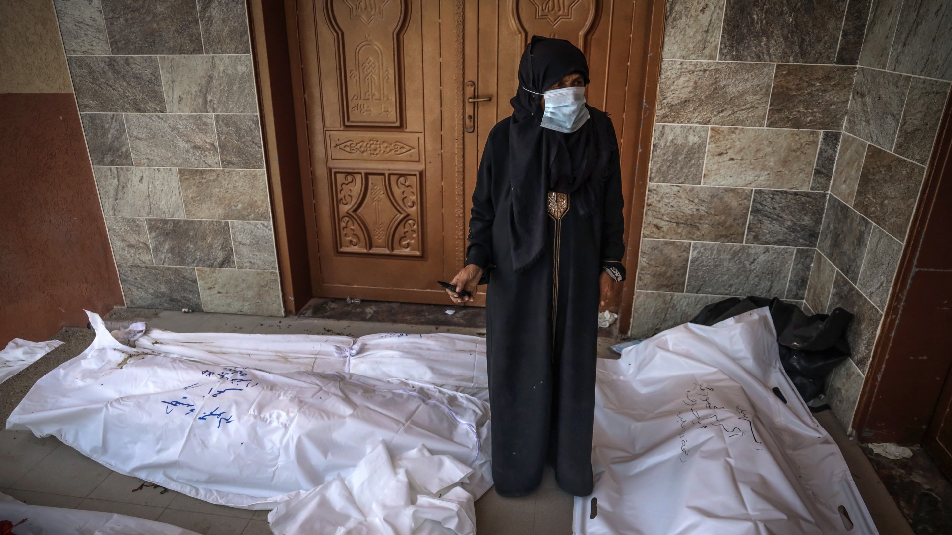 A woman marks unidentified bodies unearthed at Nasser hospital in Khan Younis in southern Gaza (AFP)