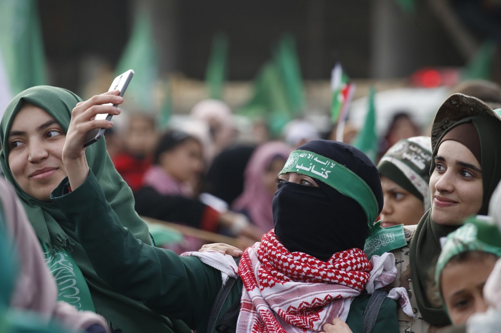 A woman takes a selfie as Palestinians attend a rally marking the 31st anniversary of Hamas' founding, in Gaza City on 16 December 2018 (AFP)