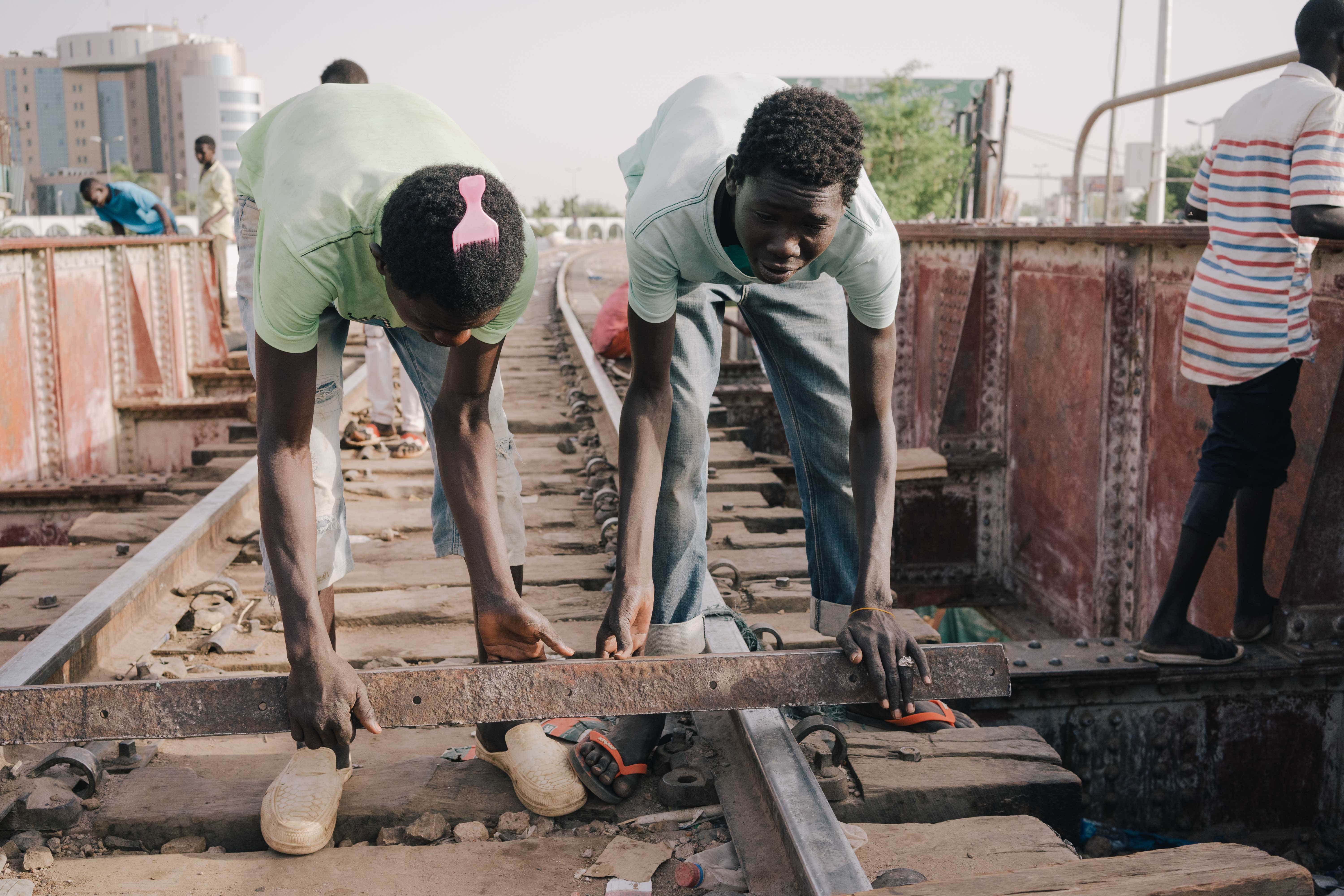 Sudanese youths beat a rhythm on a metal railway bridge in Khartoum (MEE/Kaamil Ahmed)