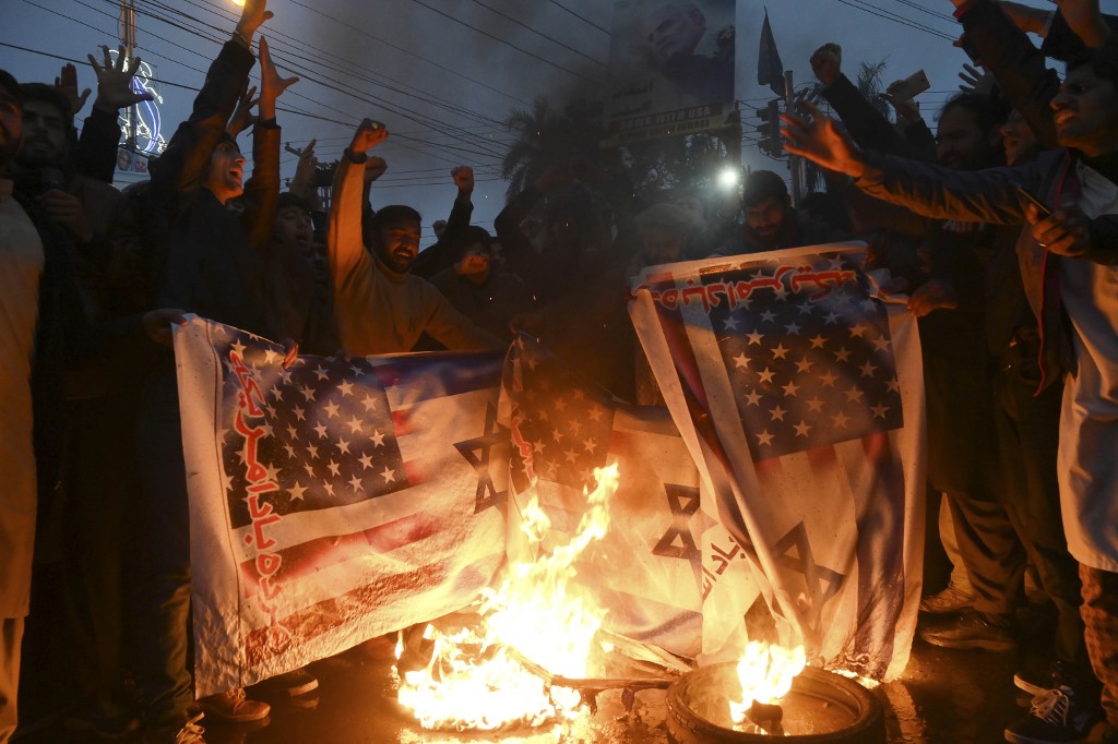 Protesters in Lahore, Pakistan, burn US and Israeli flags after the US assassination of Iranian commander Qassem Soleimani on 7 January (AFP)