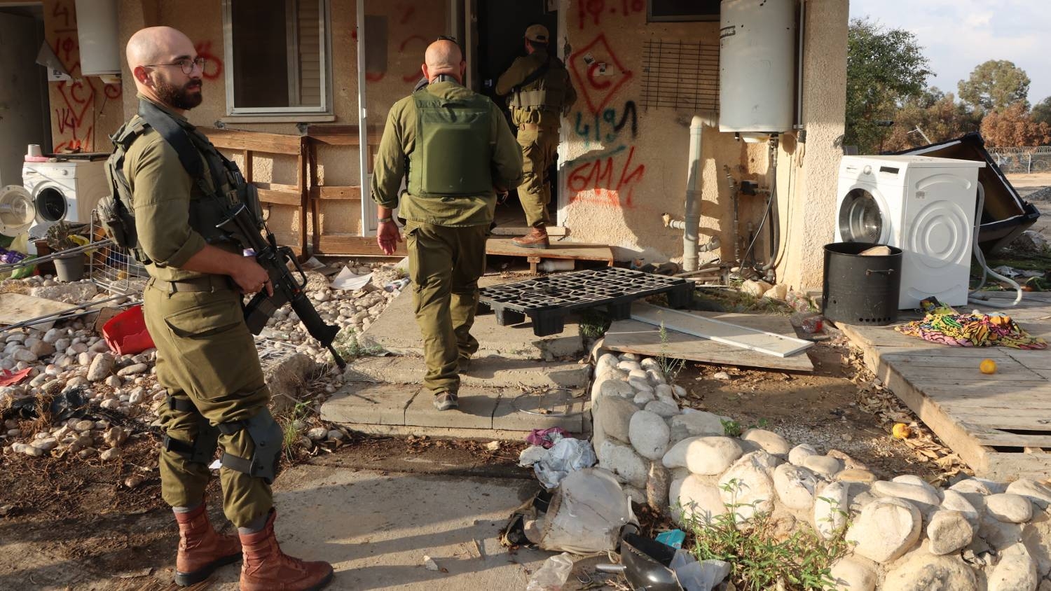 Israeli soldiers secure the area as volunteers from the Zaka emergency response team search the homes and grounds in Kibbutz Kfar Aza, near the border with Gaza on 14 November 2023.