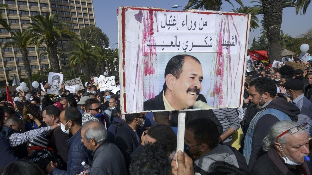 A Tunisian protester lifts a placard demanding to know who assassinated prominent leftist opposition leader Chokri Belaid, during a demonstration against the government and police repression while marking the 8th anniversary of his death, in the capital Tunis on 6 February 2021 (AFP)