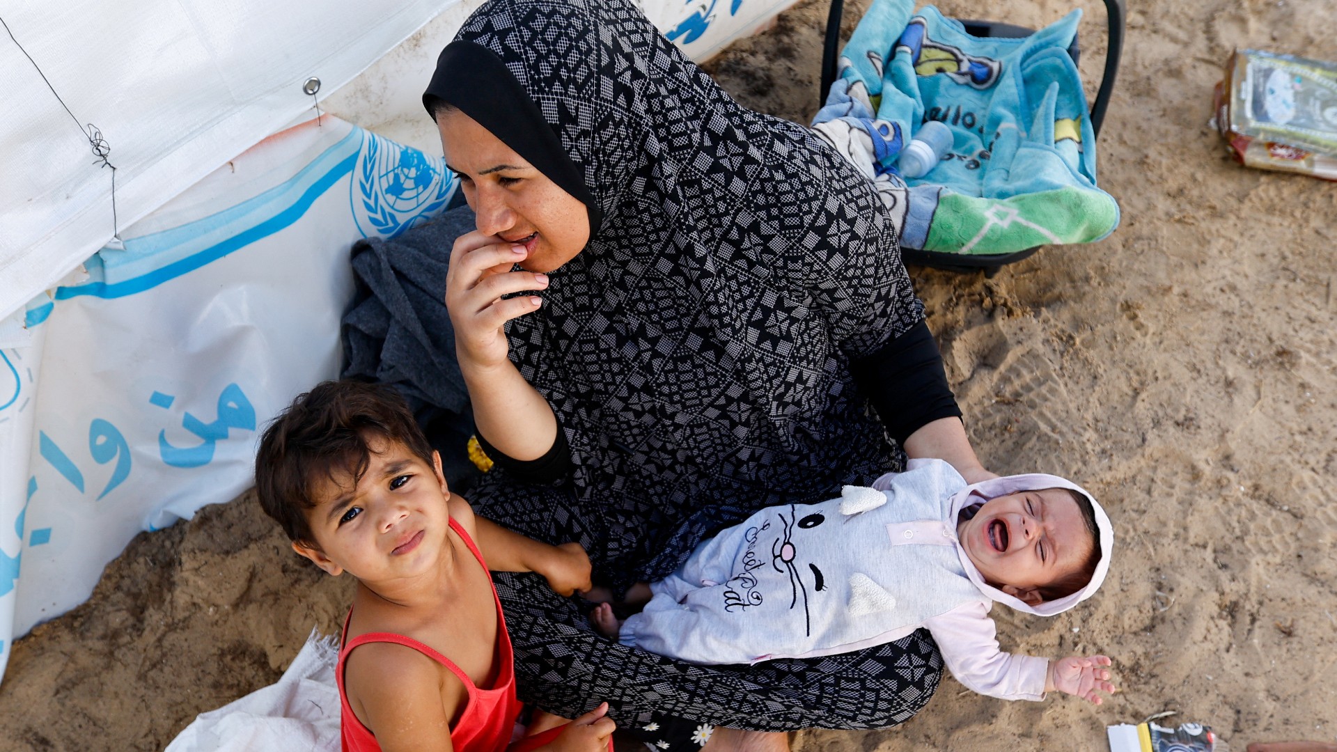 Une Palestinienne et ses enfants assis dans une tente de l’ONU accueillant des personnes déplacées à Khan Younès (Reuters)