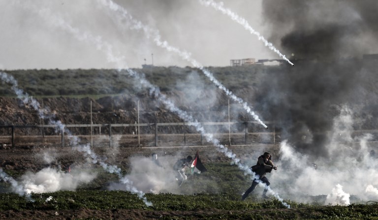 Palestinian protesters run from tear gas fired by Israeli troops in Gaza on 25 January (AFP)