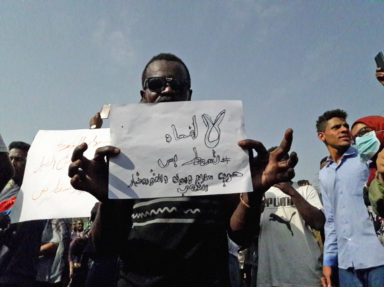A Sudanese protester holds a placard with an anti-corruption slogan on 31 January (AFP)