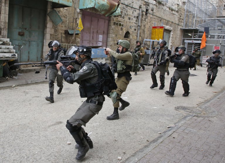 Israeli soldiers shoot rubber-coated metal bullets at Palestinian protesters in Hebron on 22 February (AFP)