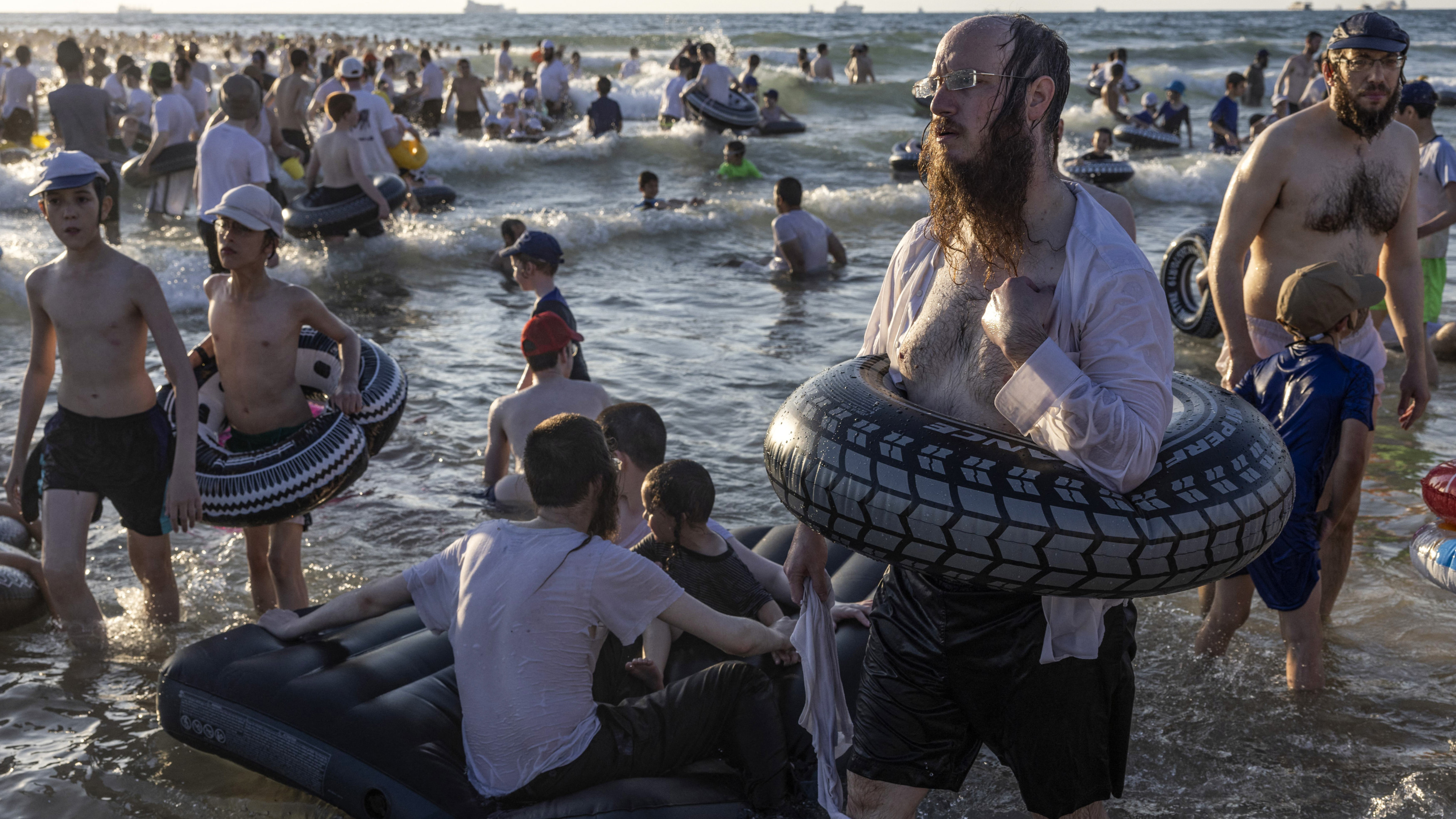 Ultra-Orthodox Jews swim at a beach reserved for men only on the coast of Ashdod during a vacation for yeshivas on 9 August 2023 (AFP)