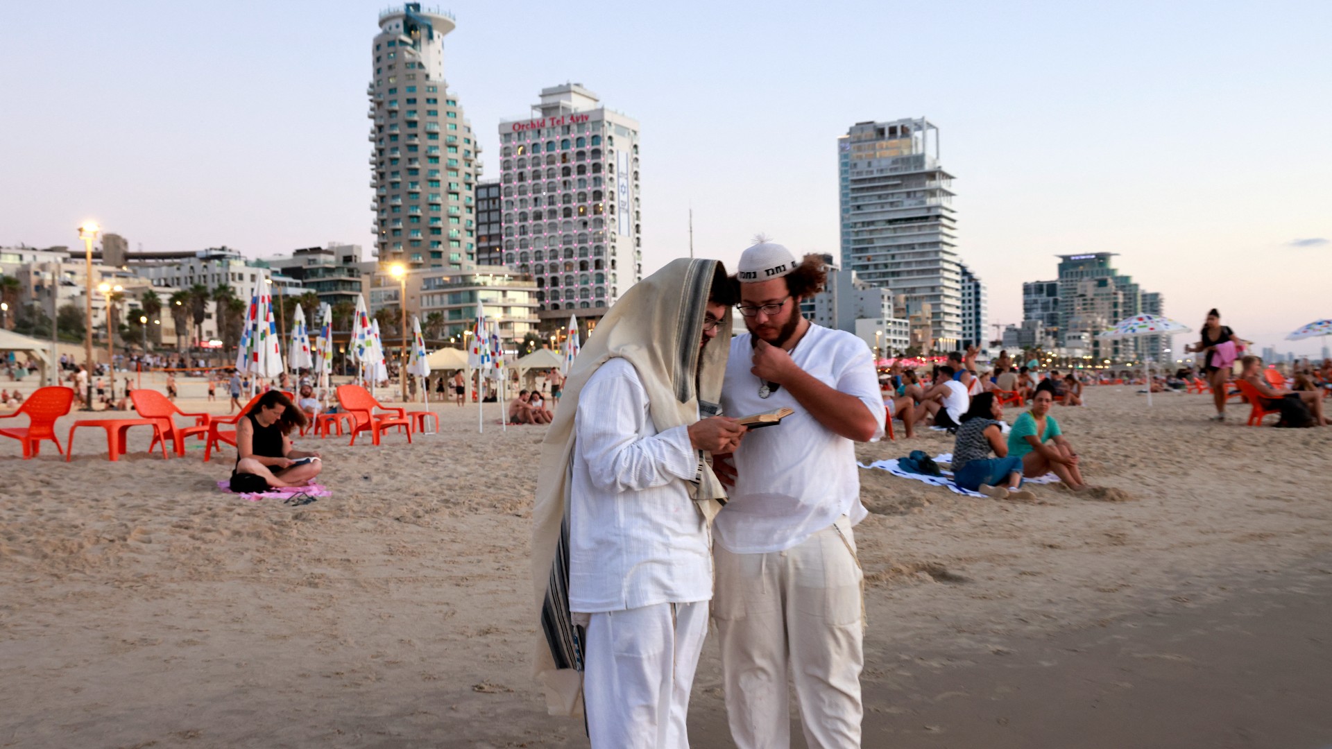 Religious men read from a book on Tel Aviv's shore (AFP)