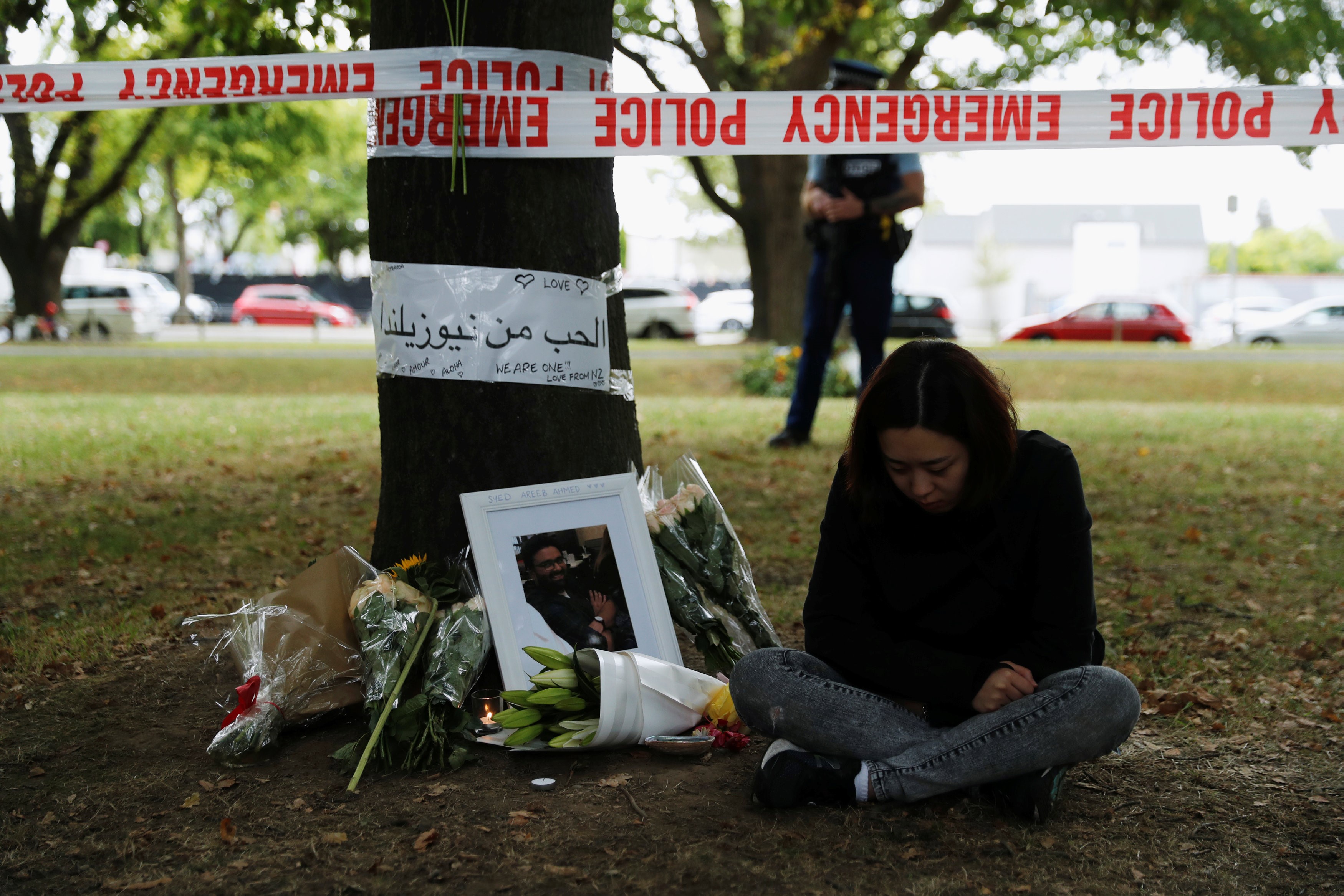    A woman sits next to flowers and messages displayed at a memorial site for victims of Friday's shooting, in front of the Masjid Al Noor mosque in Christchurch, New Zealand 18 March, 2019 (REUTERS)