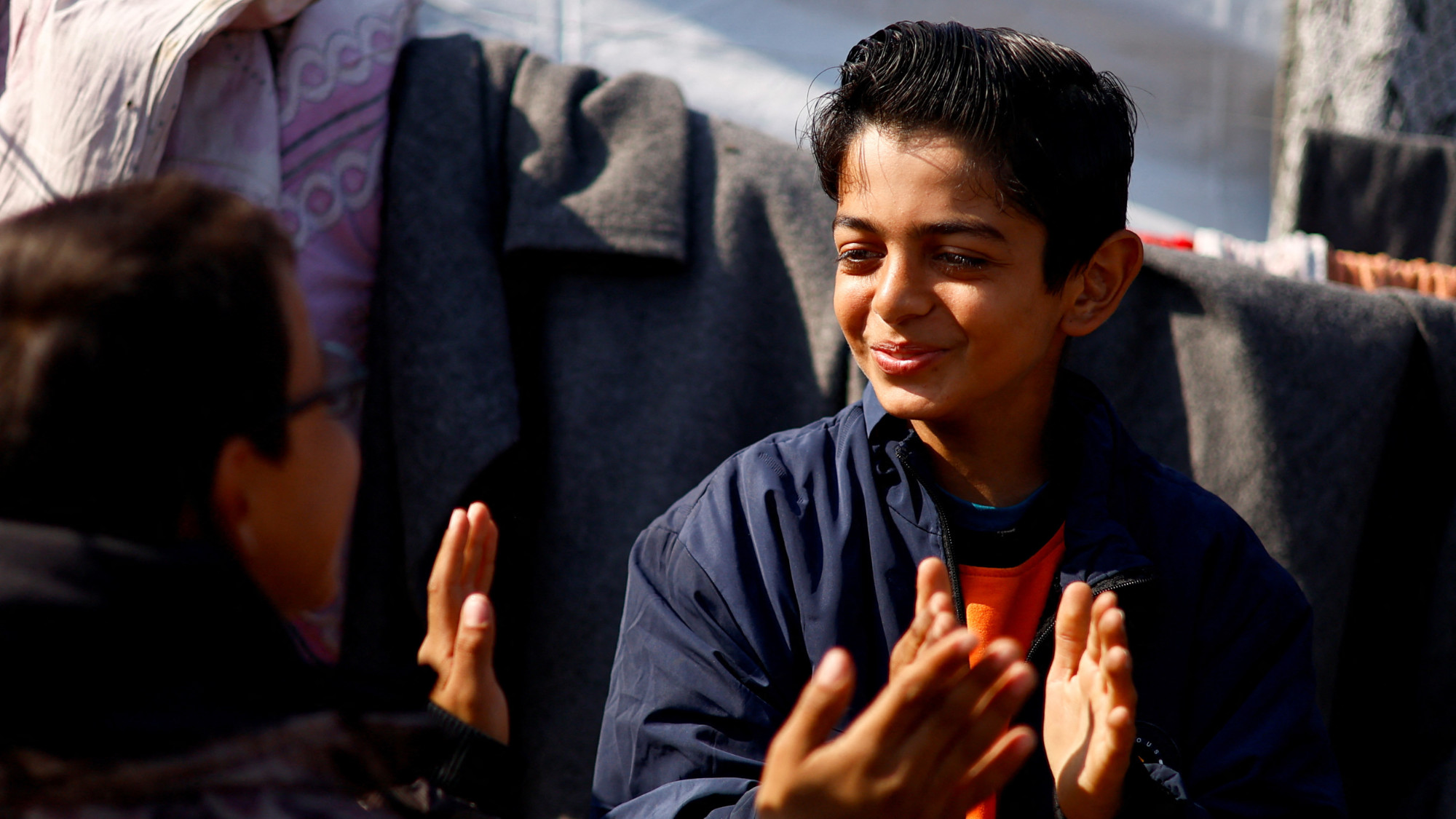 Displaced Palestinian teenager Hussam Al-Attar, nicknamed by people 'Newton', gestures at a tent camp in Rafah, in the southern Gaza Strip, 6 February 2024 (Ibraheem Abu Mustafa/Reuters)