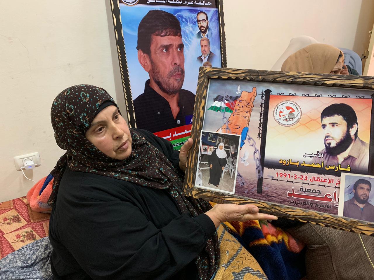 Faris Baroud's sister holds a picture of him and their mother (MEE/Hind Khoudary)