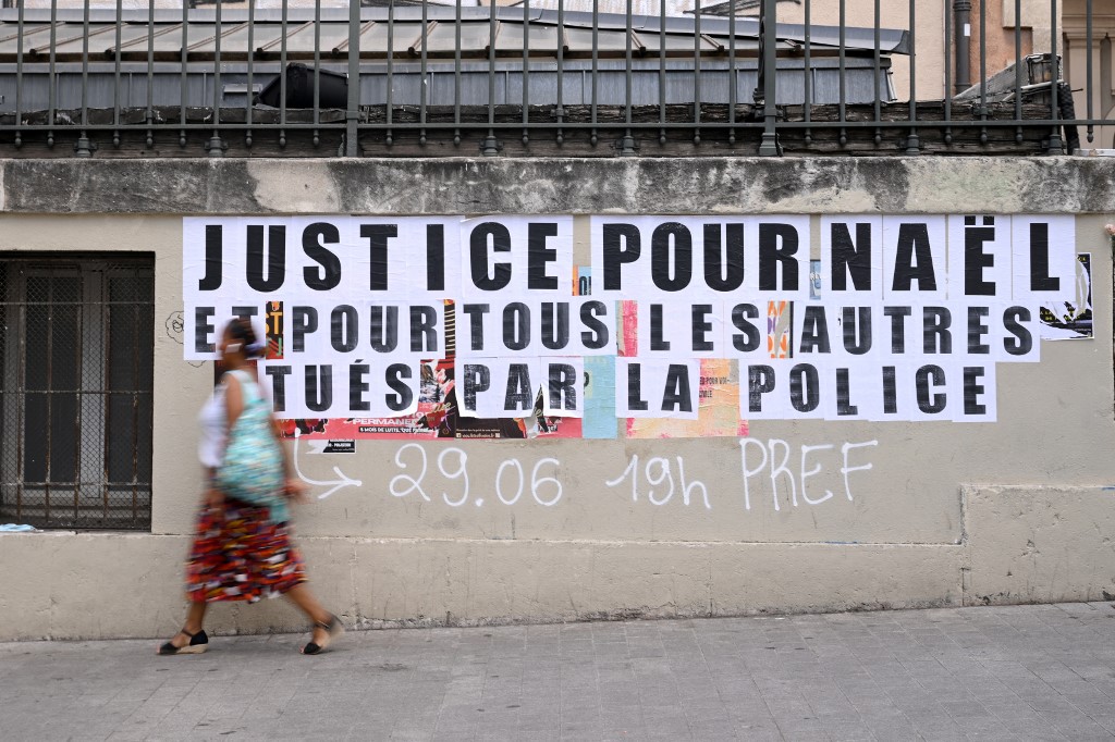 A pedestrian walks past placards reading 'justice for Nahel and for all the others killed by police' in Marseille, France, 30 June 2023 (AFP)