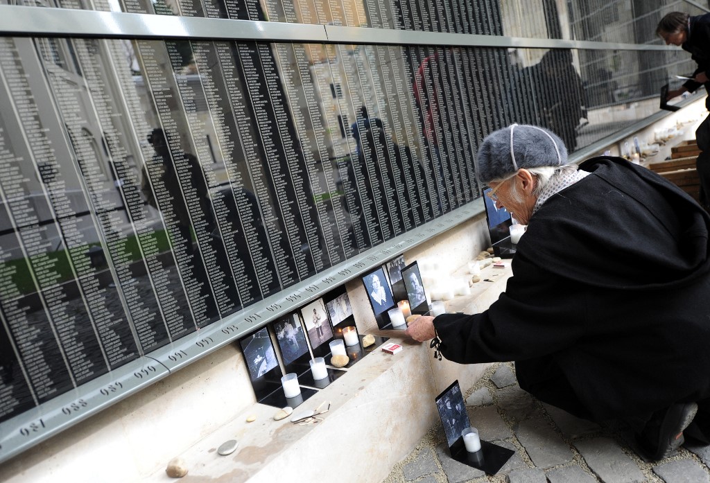 A woman places photographs of her relatives at the Holocaust Memorial Centre in Budapest, where names of Hungarian victims of the Nazi death camps are displayed, 16 April 2012 (AFP)
