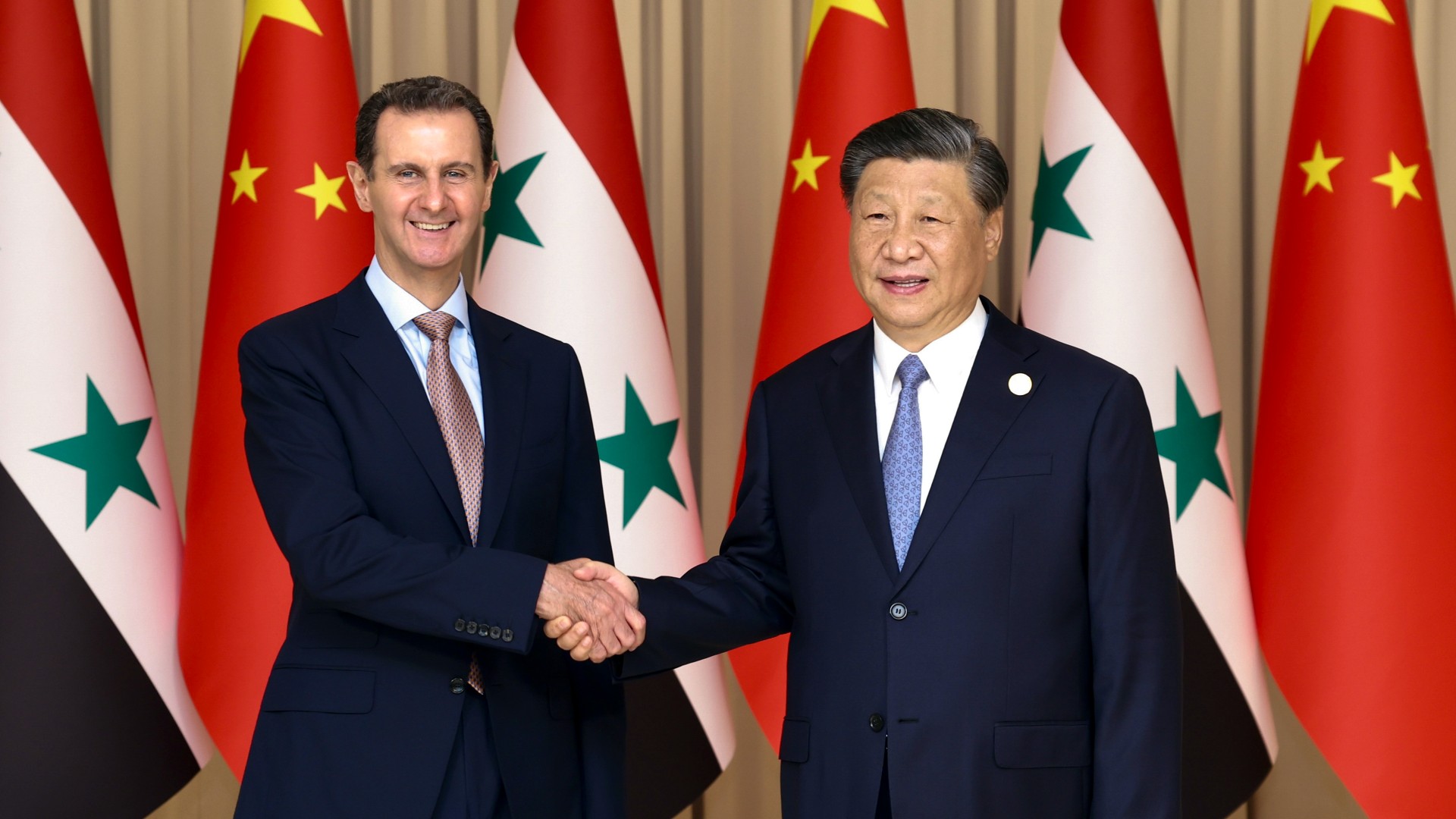 Chinese President Xi Jinping, right, shakes hands with Syrian President Bashar Assad before their bilateral meeting in Hangzhou, China, 22 September (AP)