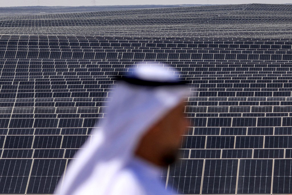 An Emirati man stands in front of photovoltaic panels at al-Dhafra Solar Photovoltaic (PV) Independent Power Producer (IPP) project south of the UAE capital Abu Dhabi, on 13 November 2023 (AFP)