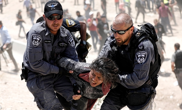 Israeli policemen detain a Palestinian girl in Khan al-Ahmar, West Bank on 4 July 2018 (Reuters)
