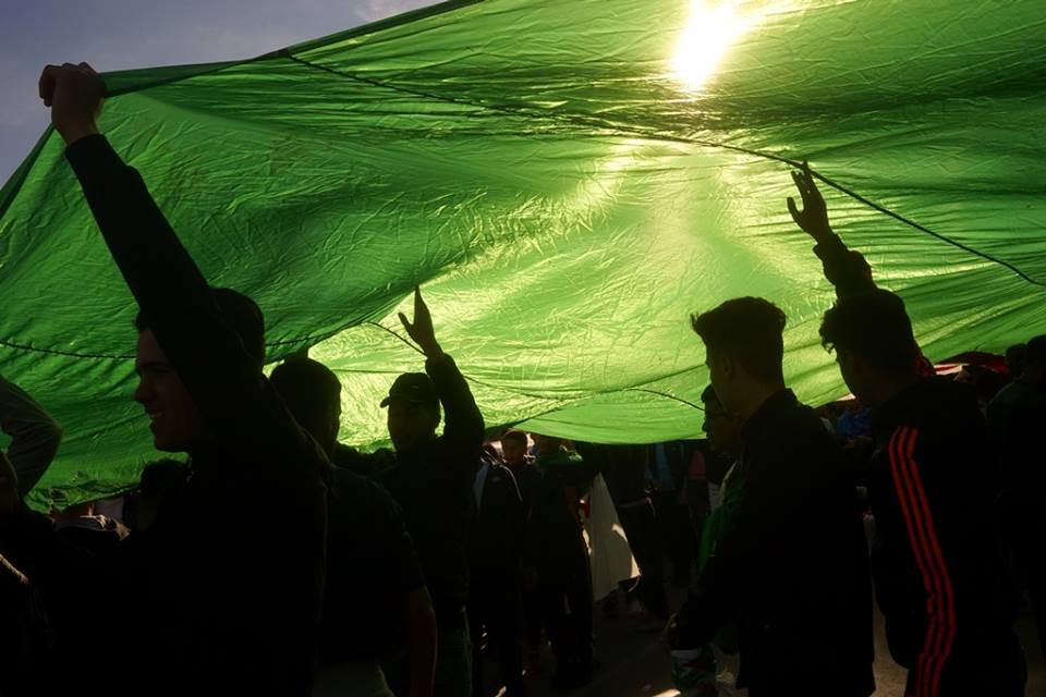 Protestors carry an Algerian flag over the heads during a recent demonstration (Houari Bouchenak)