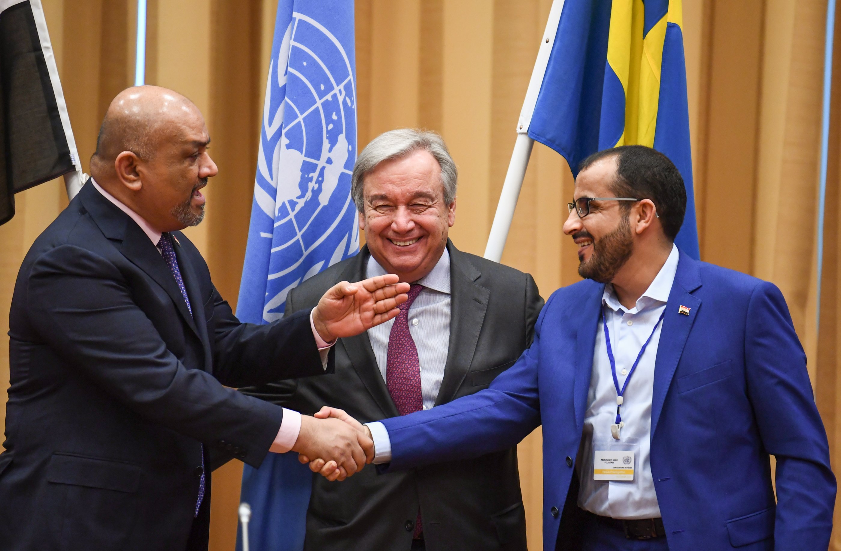Yemeni government Foreign Minister Khaled al-Yamani, left, and the head rebel negotiator Mohammed Abdelsalam, right, shake hands under the eyes of United Nations Secretary-General Antonio Guterres, centre, during peace consultations taking place at Johannesberg Castle in Rimbo, north of Stockholm, Sweden, on 13 December 2018 (AFP) 