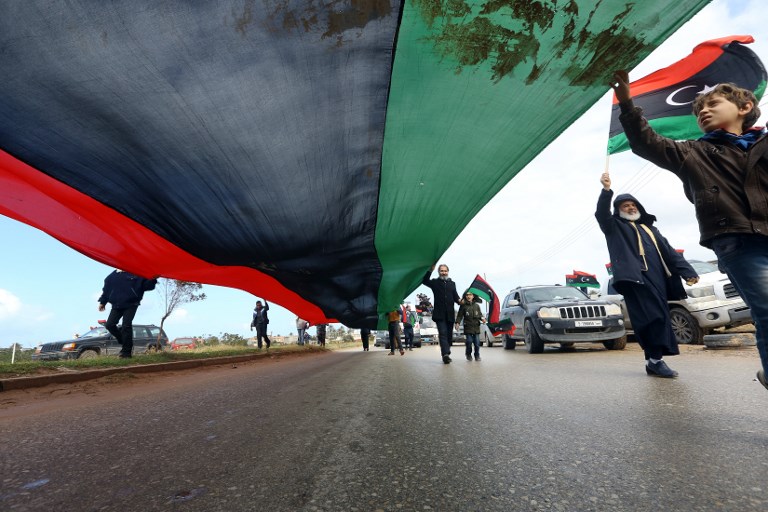 In February 2019, Libyans carry a giant national flag in the capital Tripoli to mark the the upcoming eighth anniversary of the Libyan revolution (AFP)