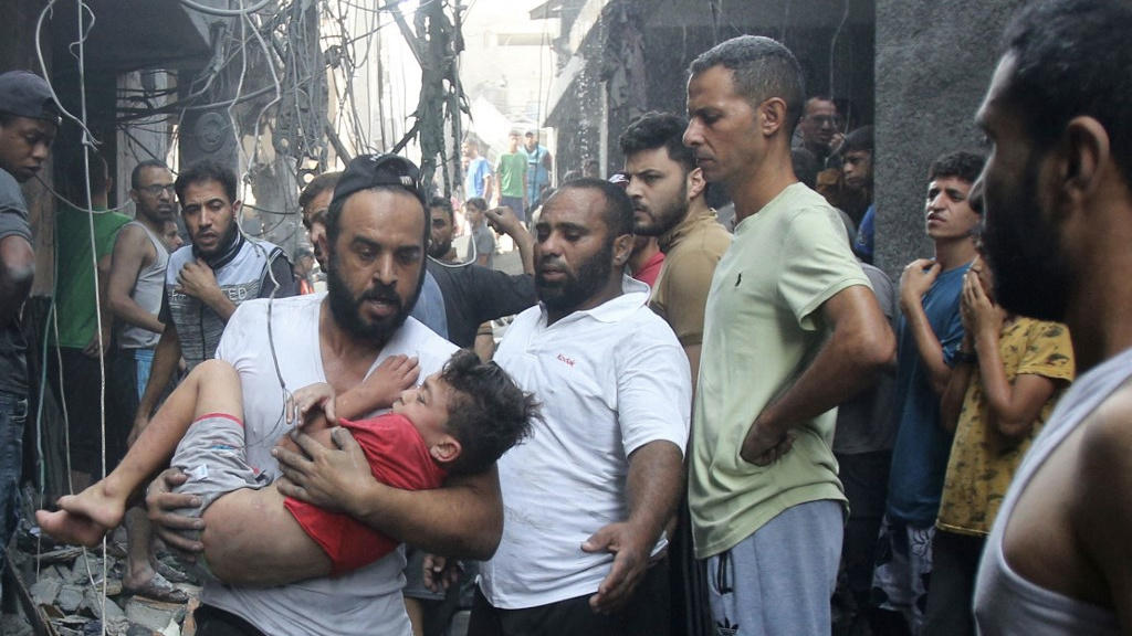 Un Palestinien porte un enfant dans ses bras après une frappe aérienne israélienne, le 12 octobre 2023 à Gaza (AFP)