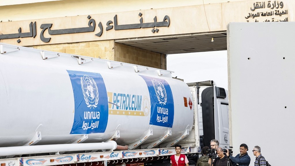 Media representatives work as a truck carrying humanitarian aid from the United Nations Relief and Works Agency for Palestine Refugees (UNRWA) arrives at the Egyptian side of the Rafah border crossing with the Gaza Strip on 22 November 2023 (AFP)