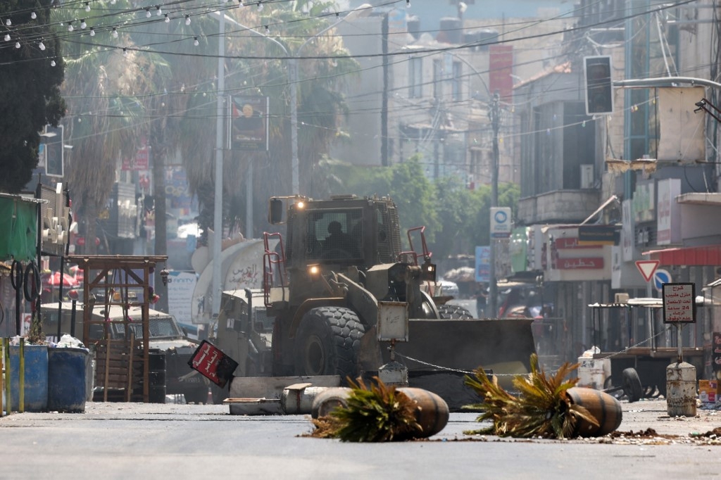 An Israeli army bulldozer drives through Jenin in the occupied West Bank during a military operation on 3 July (AFP)