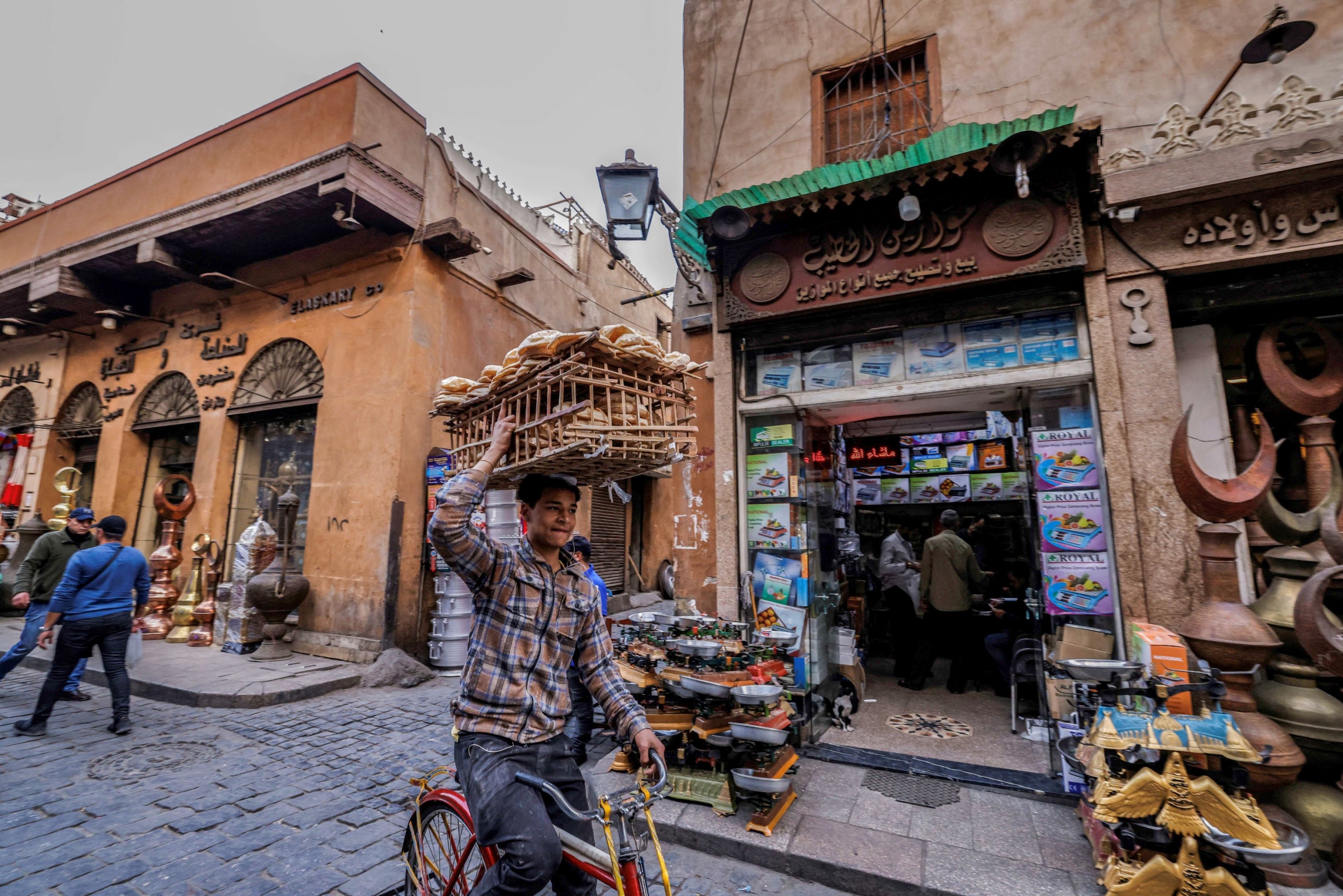 A deliveryman balances a load of bread on his head as he cycles through the old quarters of Cairo