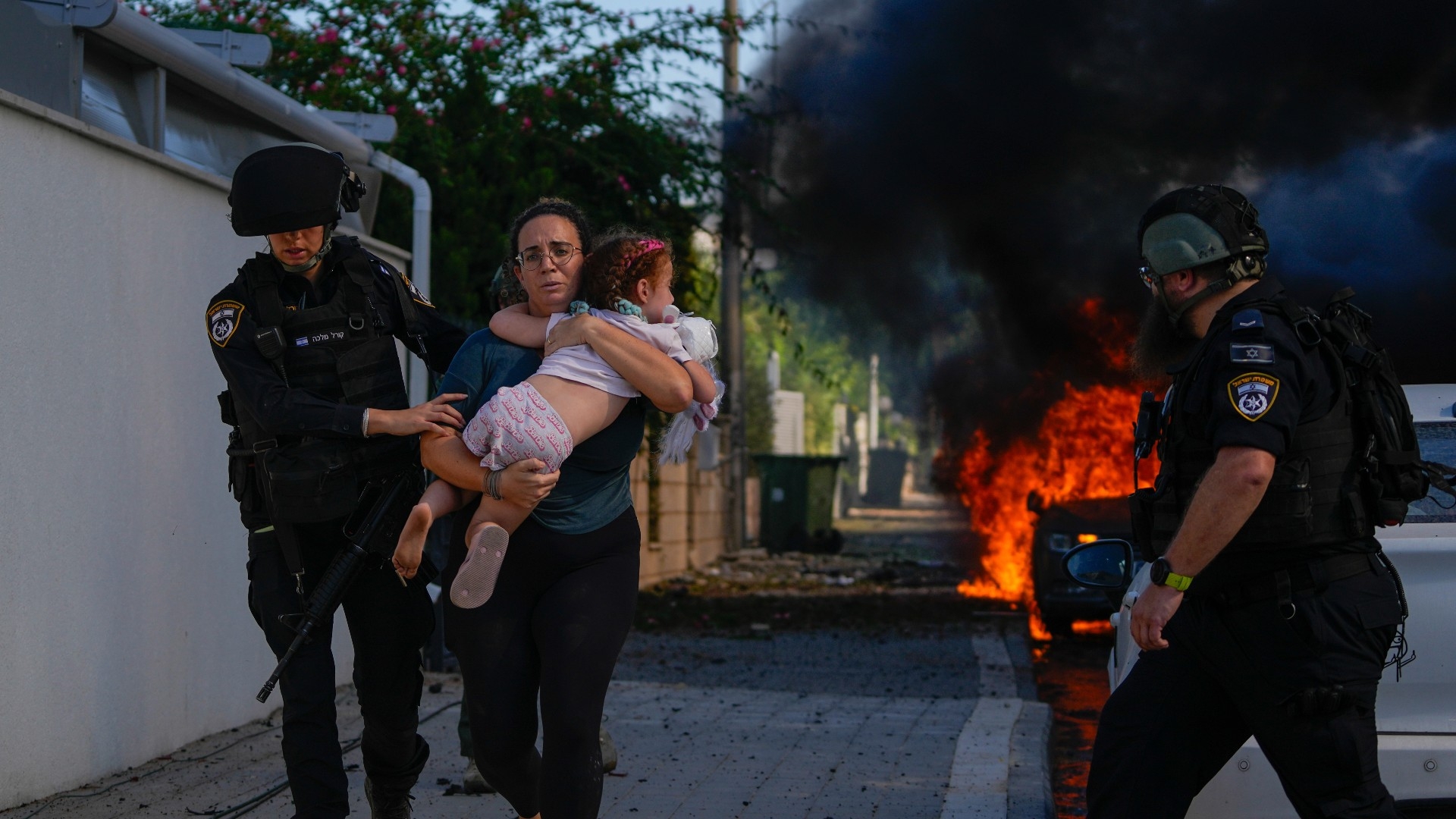 Police officers evacuate a woman and a child from a site hit by a rocket fired from the Gaza Strip, in Ashkelon (AP)
