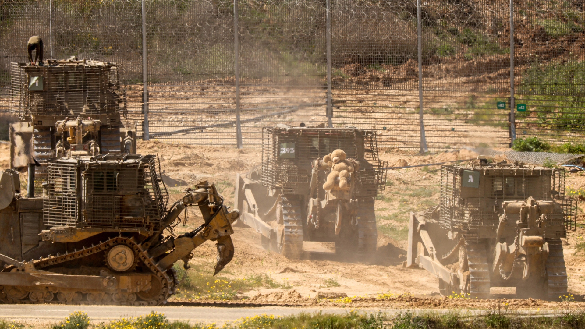 An Israeli soldier operates a military armoured bulldozer adorned with a large stuffed bear along Israel's southern border with Gaza on 21 March amid Israel's ongoing war on the strip (Jack Guez/AFP)