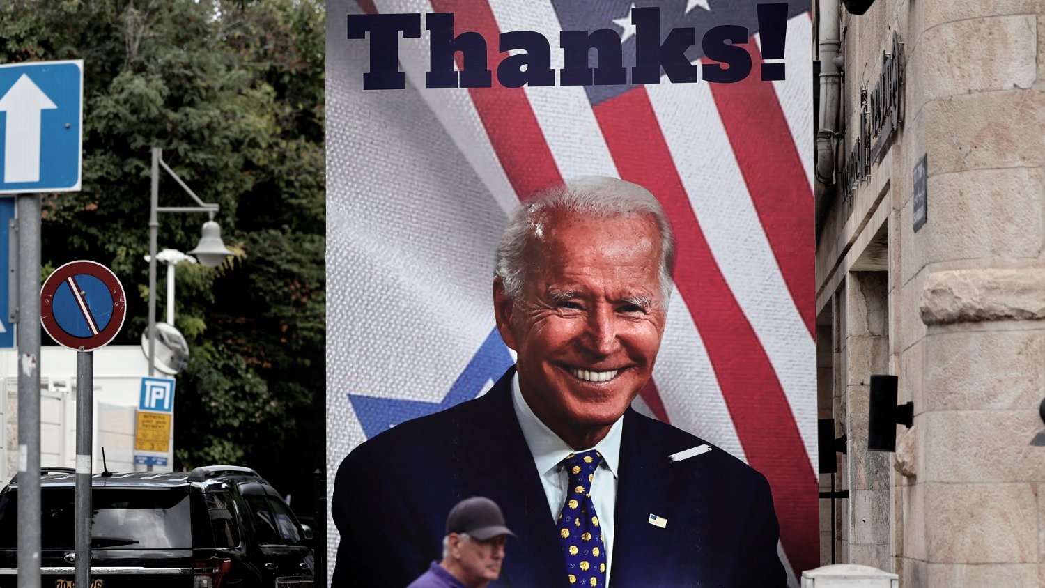 A man walks past a giant poster of US President Joe Biden in a street of Jerusalem on 20 October 2023.