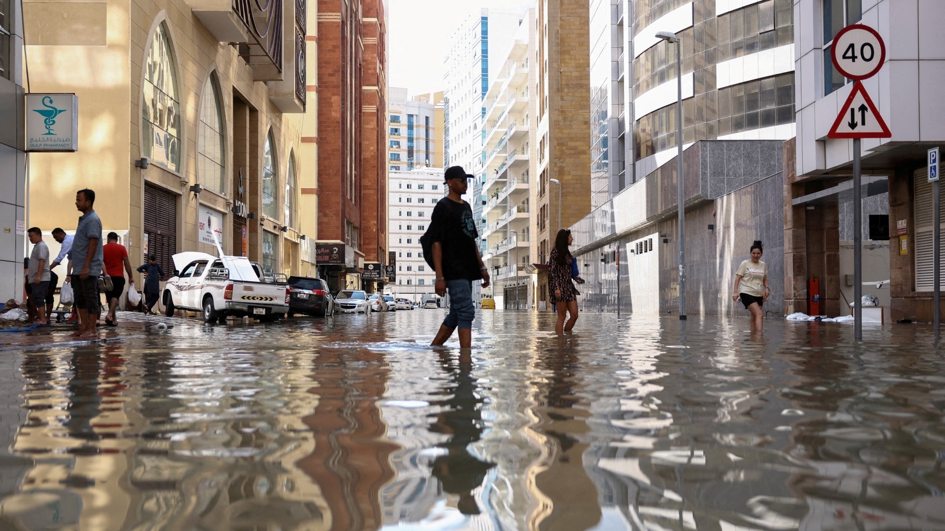 People walk through flood water caused by heavy rains, in Dubai, United Arab Emirates on 17 April 2024 (AFP/Amr Alfiky)