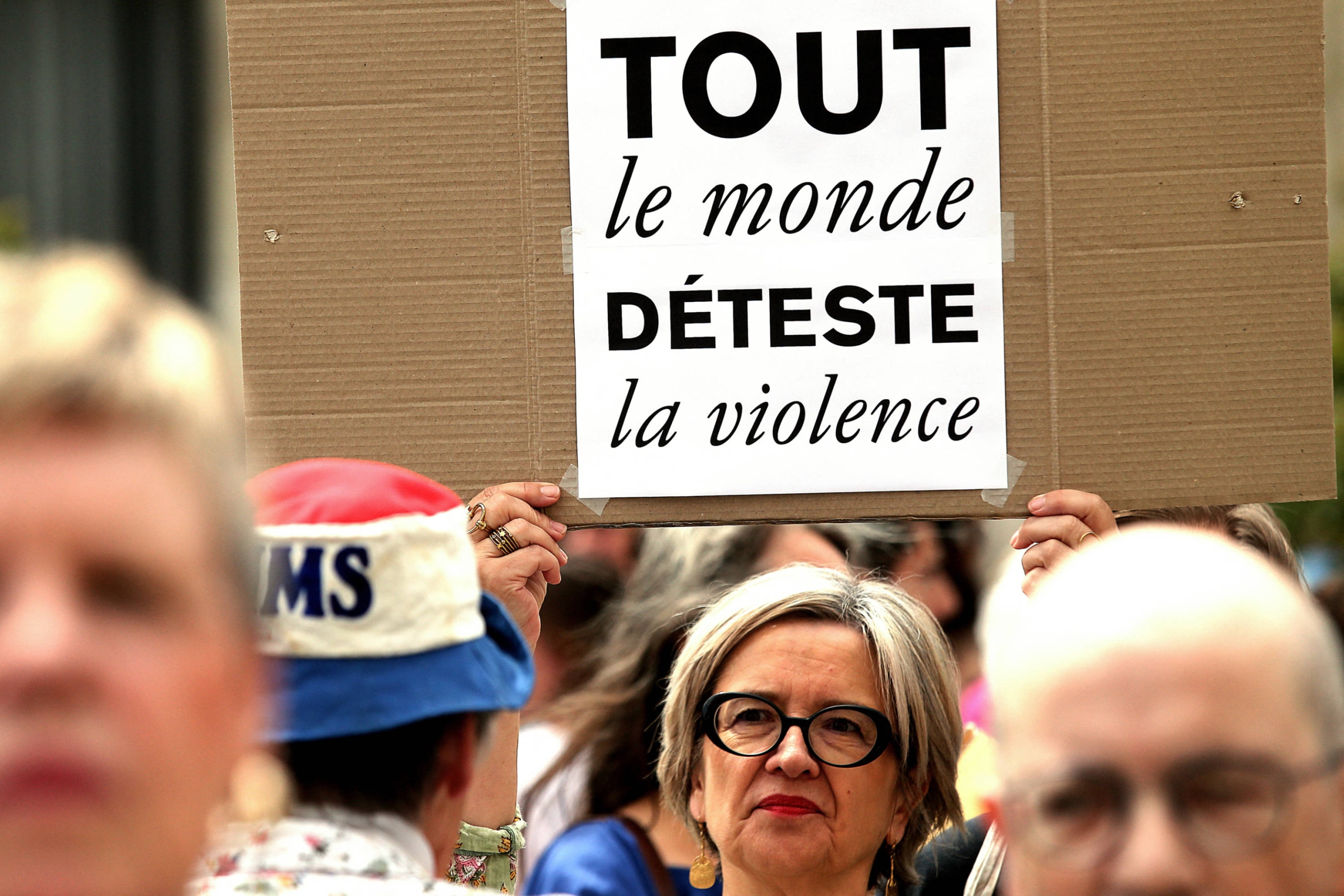 A woman holds up a placard that reads "everyone hates violence" as participants take part in a nationwide anti-riot rallies in Reims, northern France, on 3 July 2023 (AFP)