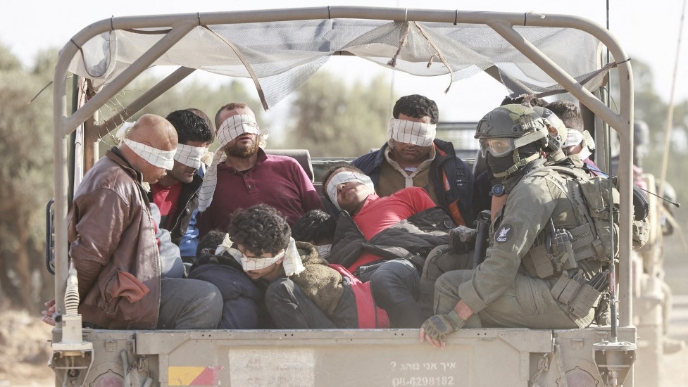 Israeli soldiers transfer detained Palestinians out of the Gaza Strip on 21 November 2023 (Menahem Kahana/AFP)