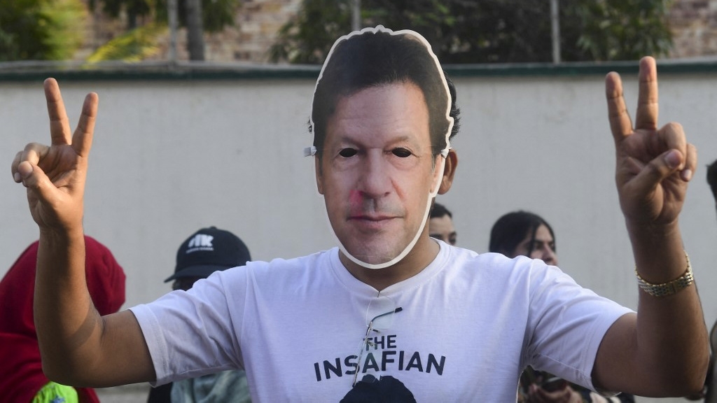 A supporter of jailed former leader Imran Khan wears a mask bearing his likeness during protests against alleged vote-rigging in Karachi, Pakistan, on 11 February 2024 (Asif Hassan/AFP)