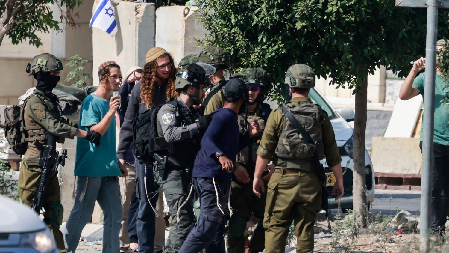 Israeli soldiers restrain settlers trying to storm the town of Deir Sharaf in the Nablus governorate of the occupied West Bank on 2 November 2023.