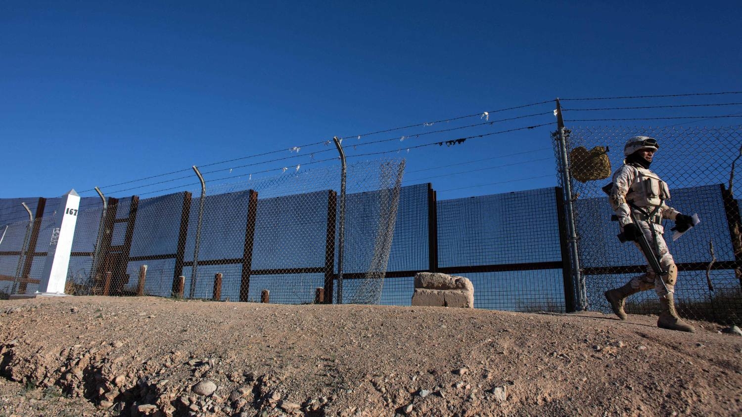 A Mexican soldier walks along a section of the US-Mexico border fence in Sonoyta, on 16 February 2017.