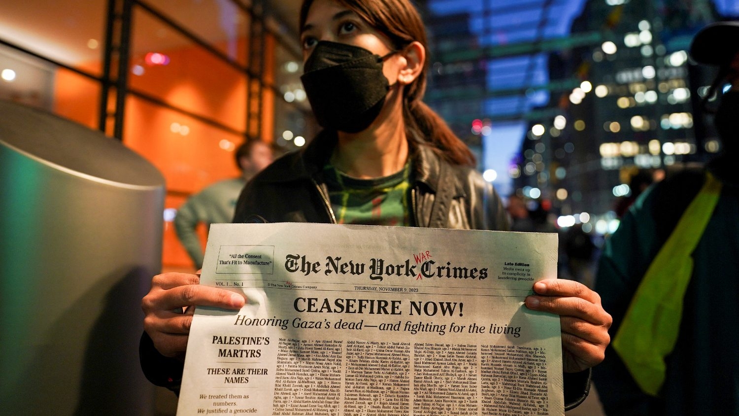 A woman holds a fake newspaper with a list of names of people killed in Gaza outside the offices of The New York Times in New York City, on 9 November 2023 