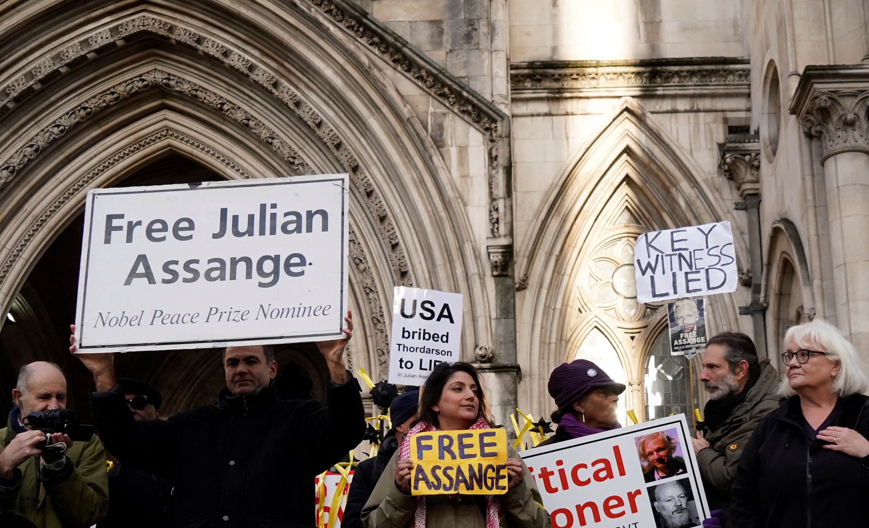 Supporters of WikiLeaks founder Julian Assange, hold placards outside the Royal Courts of Justice in London on December 10, 2021. 