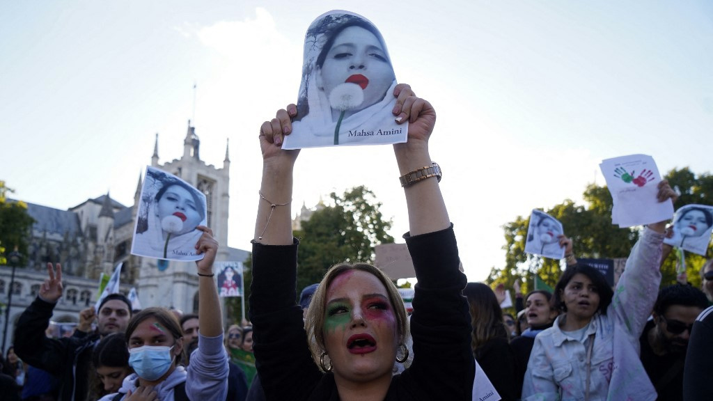 Des manifestants scandent des slogans et brandissent des photos de Mahsa Amini, tuée en détention par la police iranienne, lors d’une manifestation dans le centre de Londres, le 8 octobre 2022 (Niklas Hallen/AFP)